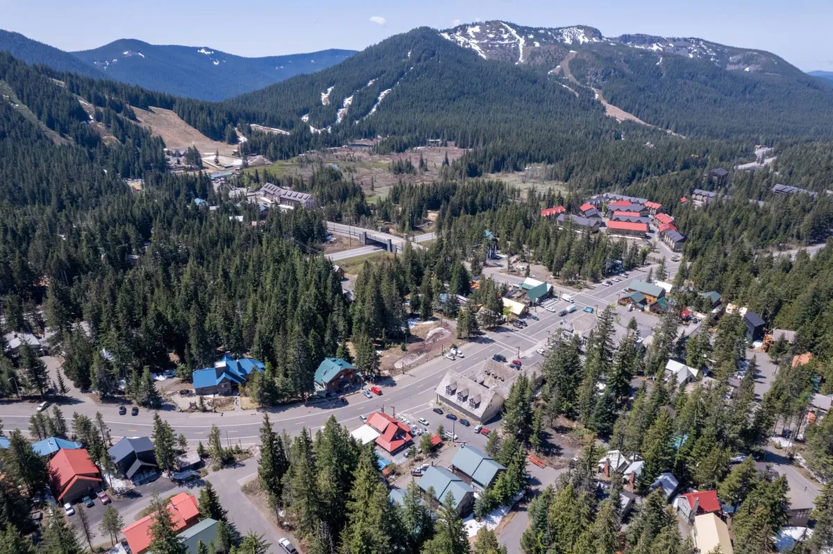 Captured from a vantage point, this image presents a panoramic view of the mountainous backdrop, the layout of the local town, dense forests, winding roadways, and colorful rooftops. It radiates a sense of exploration, outdoor adventure, and the broader Mt. Hood area accessible from Nor Ski Haus A.