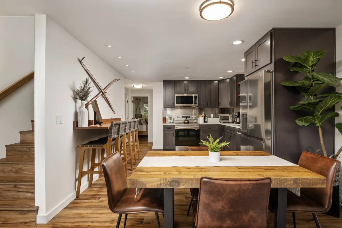 A modern kitchen and dining area with a spacious dining table, a kitchen island, stainless steel appliances, and a vibrant plant bringing life to the space—ideal for cooking, dining, and casual gatherings.